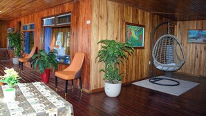 Un interior de madera con una mesa, sillas, plantas en macetas y un sillón colgante.
