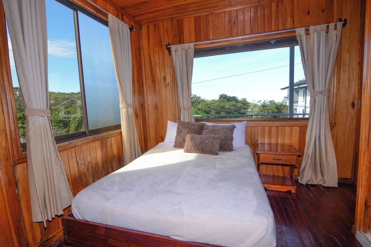 Una habitación de madera con cama, cortinas y ventana.