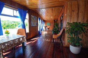 Un intérieur en bois comprenant une table à manger, des chaises, des plantes en pot et des œuvres d’art encadrées.