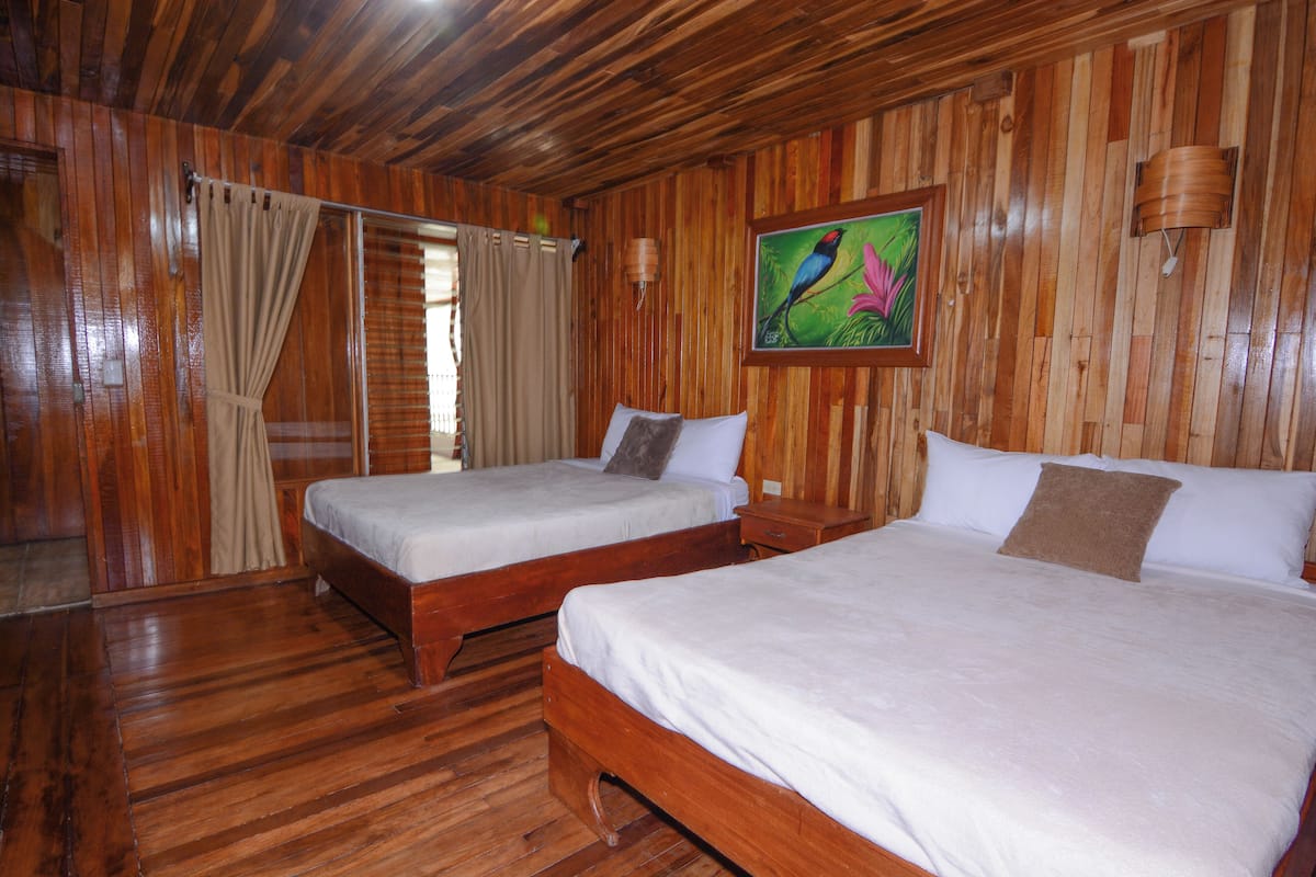 Una habitación con paneles de madera, dos camas, un cuadro y techo de madera.