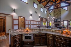 A spacious kitchen with a large island, built-in oven, and stone fireplace. - Sanctuary at Eagles Nest (Banner Elk)
