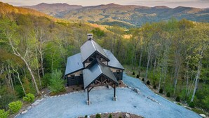 A cabin with a sloped roof, surrounded by a forested landscape and mountains in the background. - Sanctuary at Eagles Nest (Banner Elk)
