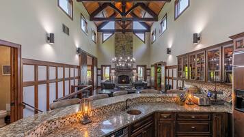 A spacious kitchen with a large island, built-in appliances, and a stone fireplace.
