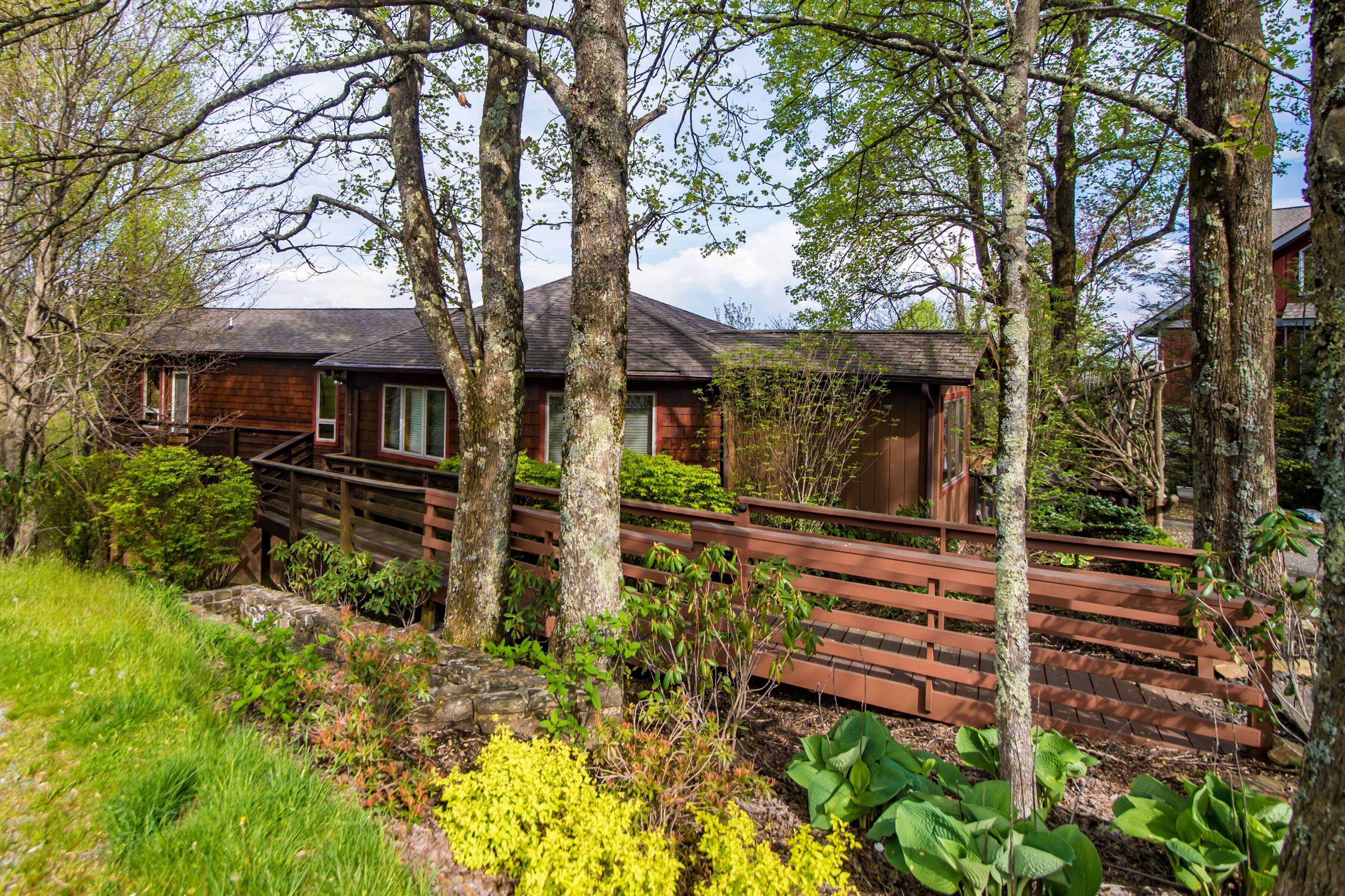 Une cabane dotée d’une terrasse en bois, entourée d’arbres et de verdure.