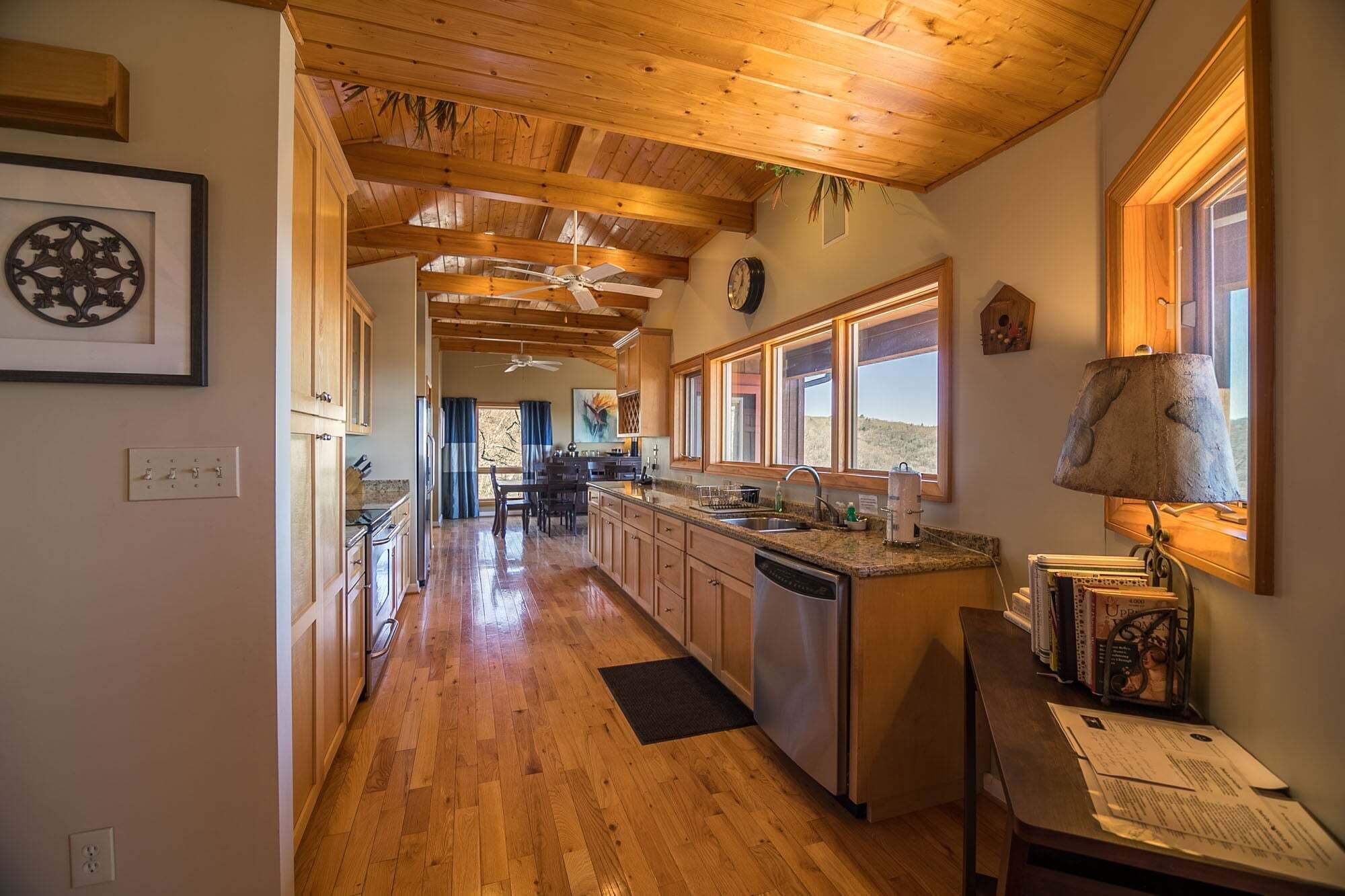 Una cocina con vigas de madera, una isla central y vistas al exterior.
