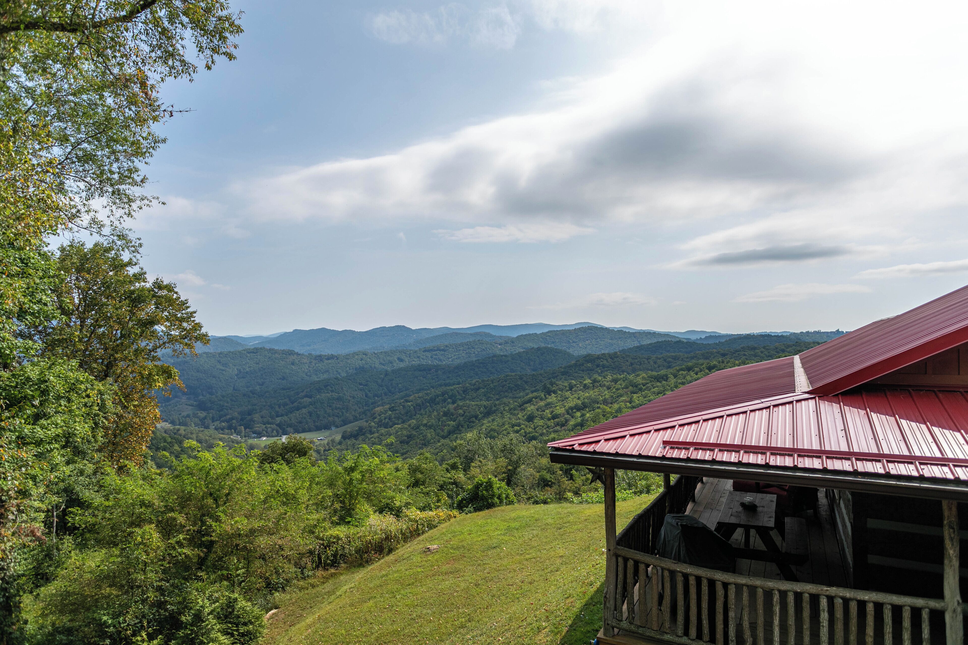 A cabin with a red roof overlooking a mountainous landscape.
