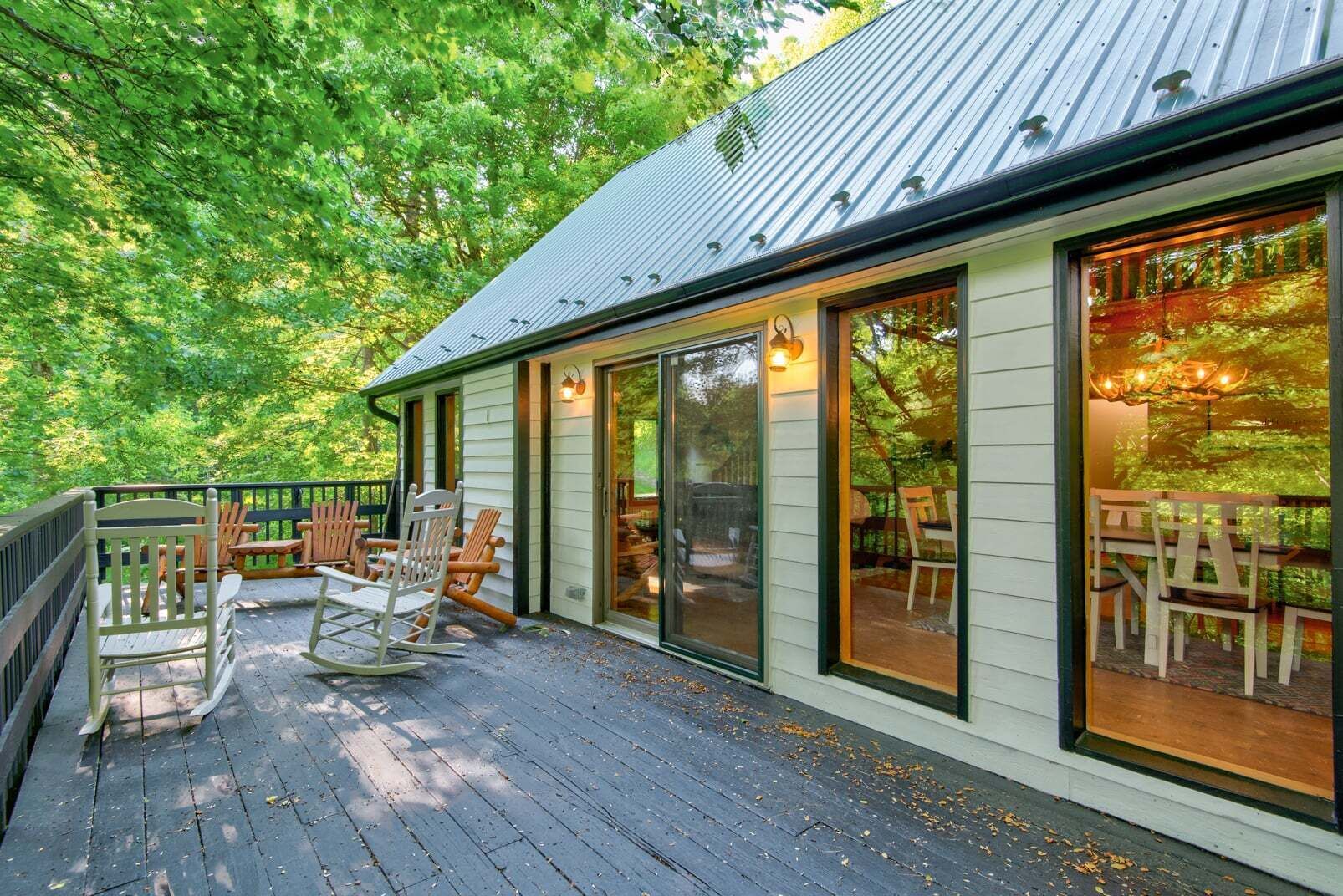 A wooden deck with outdoor seating, large windows, and a metal roof.
