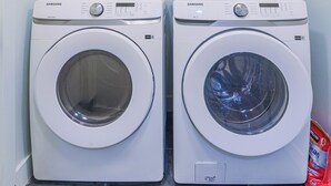 A laundry room with two Samsung washing machines, a green broom, and a red detergent packet. - 1409 #2 Sugar House (Salt Lake City)