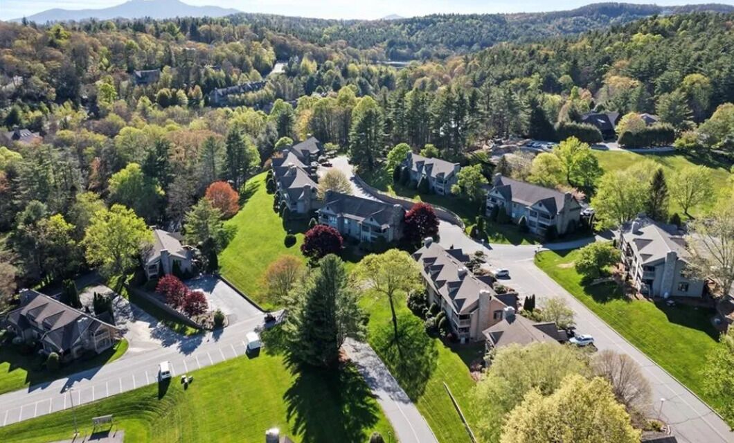 An aerial view of a residential area with houses, roads, and surrounding greenery.