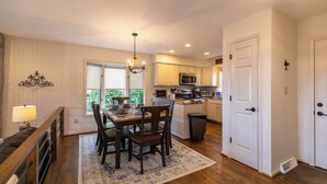 A spacious kitchen with wooden cabinets, a dining area with a table and chairs, and a chandelier.