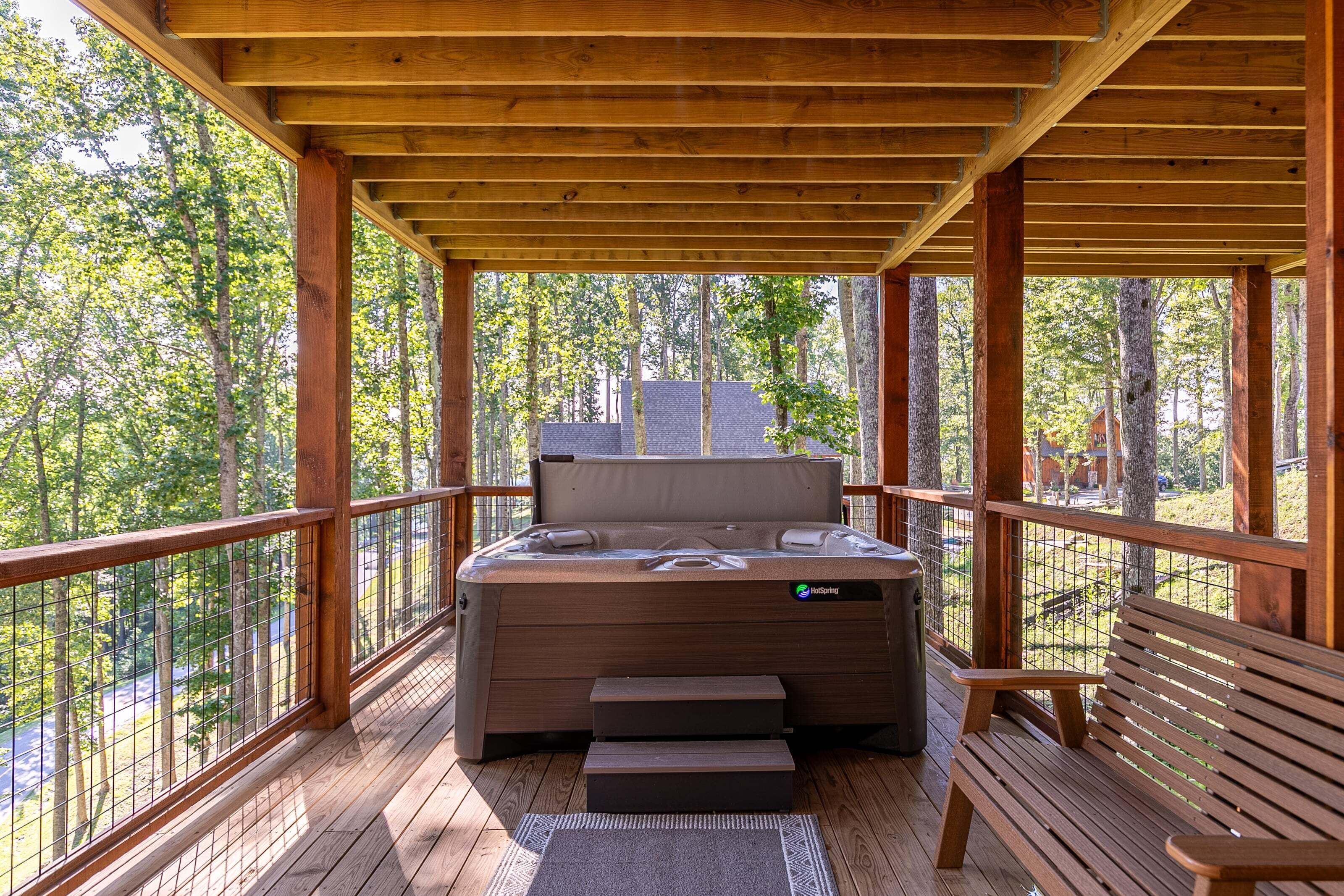 A hot tub on a wooden deck with a view of a forest.