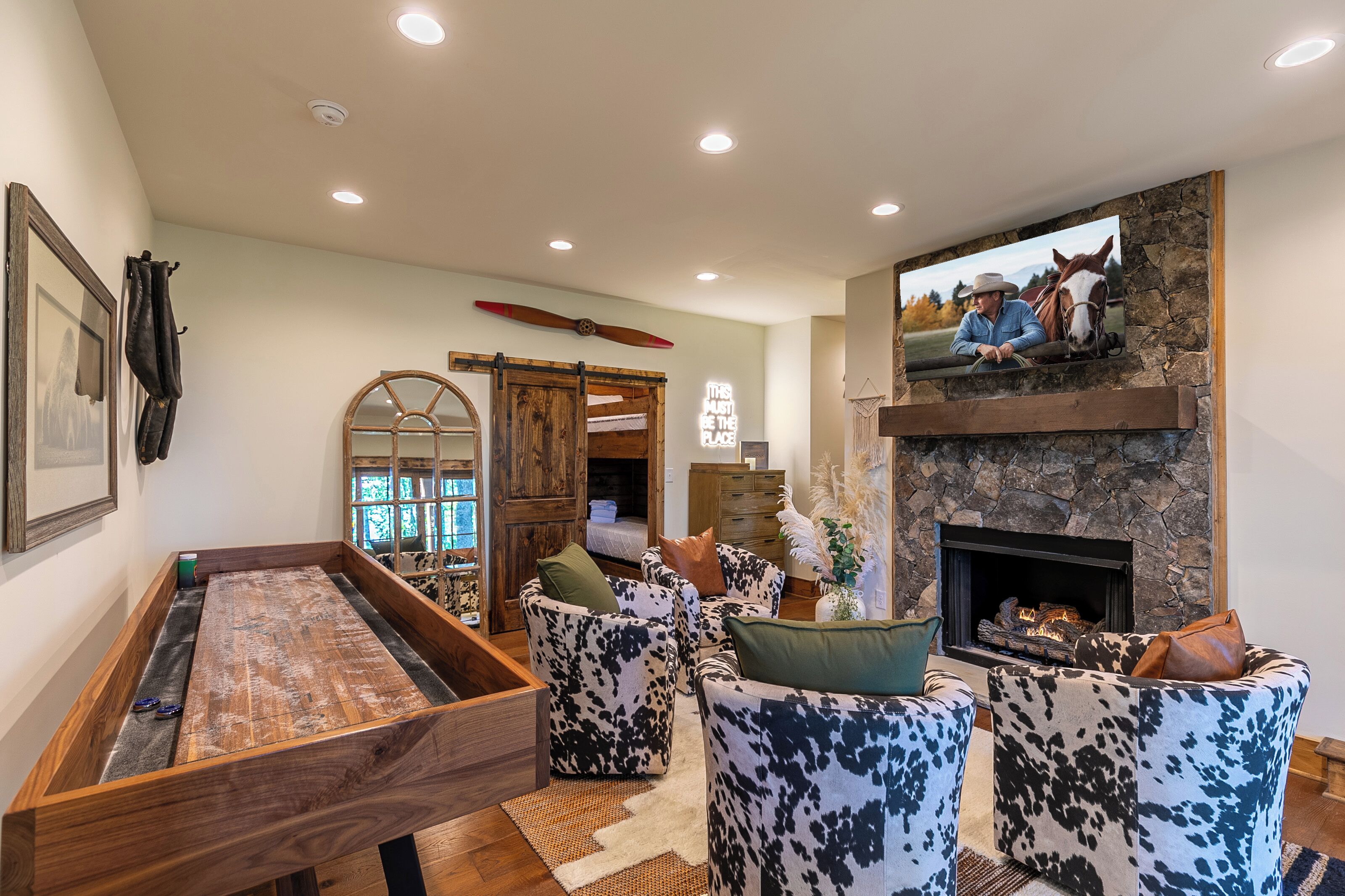 A cozy living room with a pool table, comfortable seating, a fireplace, and a mounted television.