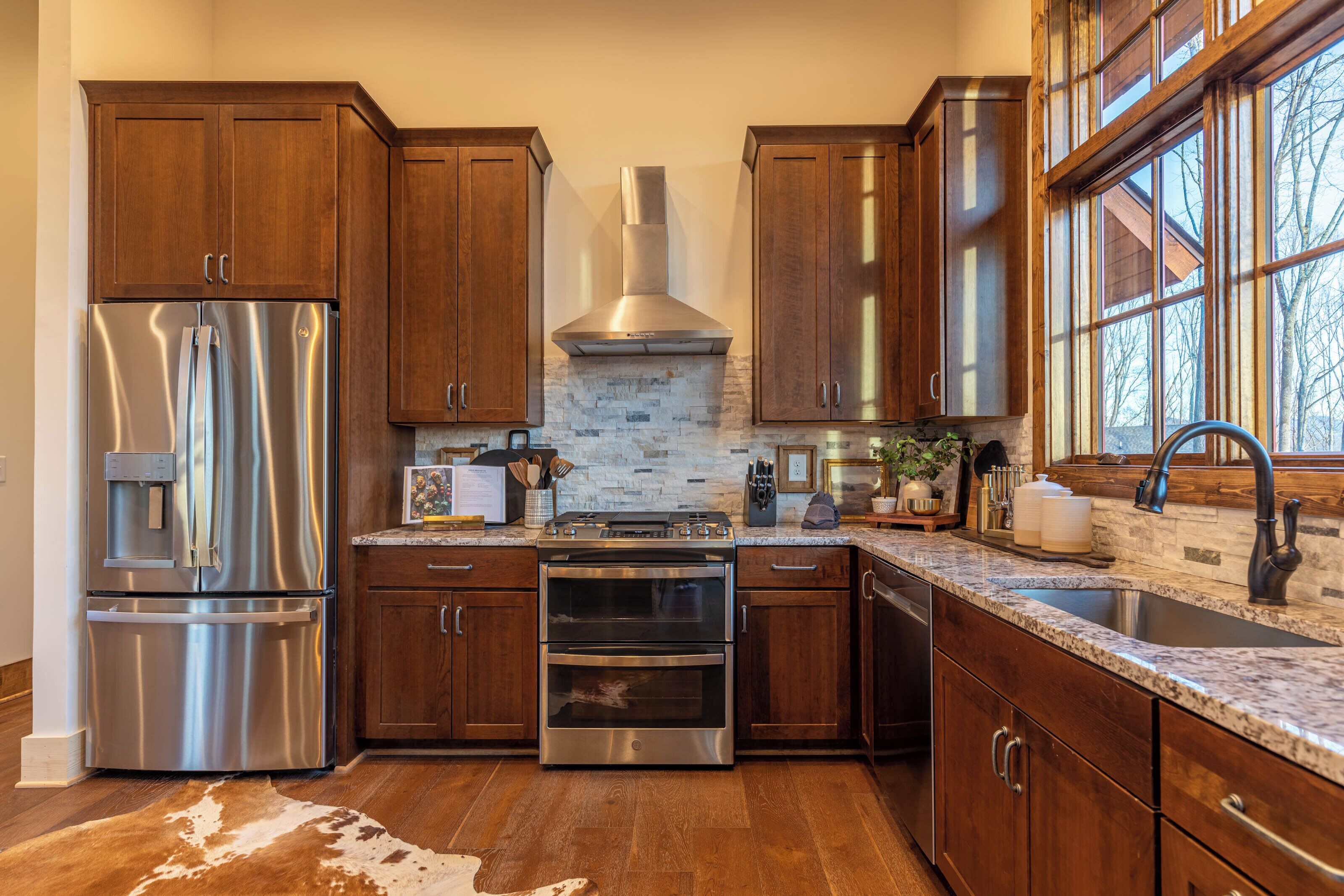 Una cocina moderna con electrodomésticos de acero inoxidable, armarios de madera y un amplio ventanal que proporciona luz natural.