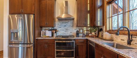 Una cocina moderna con electrodomésticos de acero inoxidable, armarios de madera y un amplio ventanal que proporciona luz natural.