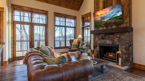 A cozy living room with a fireplace, large windows, and a comfortable seating area. - Tipsy Elk at Eagles Nest (Banner Elk)