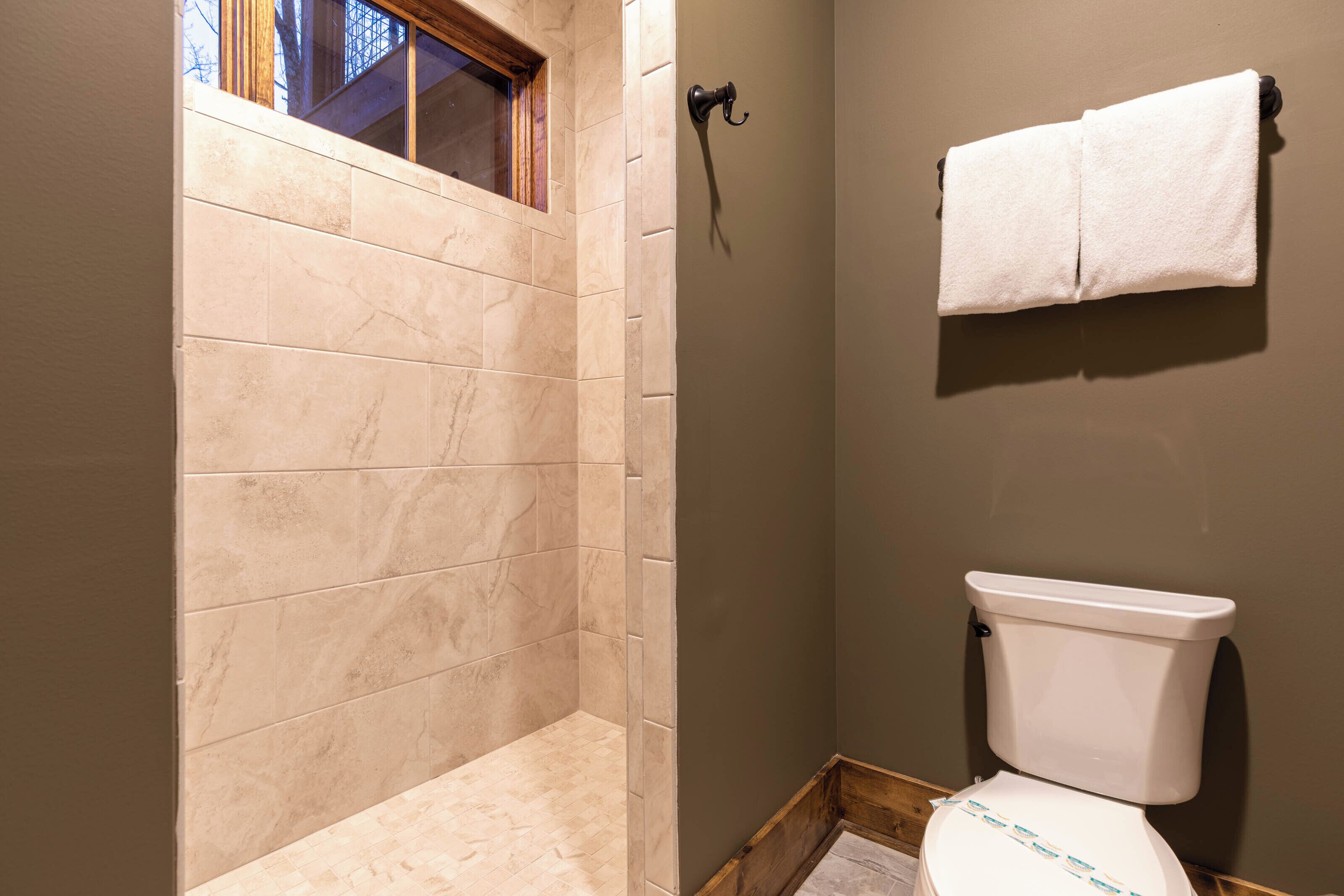 A bathroom with a shower, toilet, and a towel hanging on the wall.