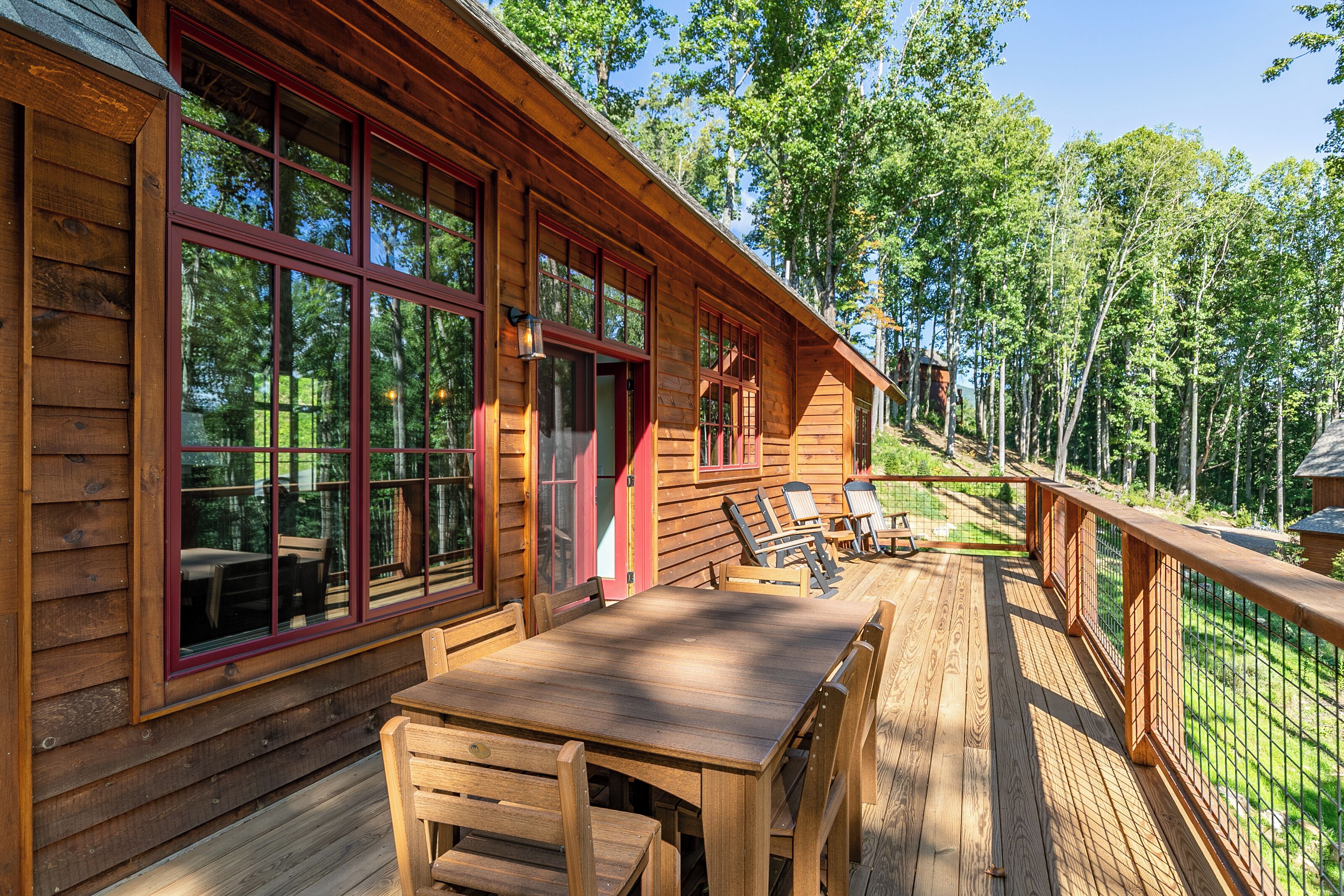 A wooden cabin with a deck, large windows, and outdoor seating.