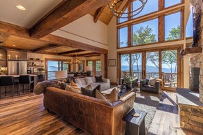 Ein großzügiger Wohnbereich mit einer großen Ledersofa, Holzböden und einem Kamin aus Stein.