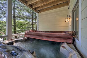 A hot tub with a wooden bench, surrounded by a wooden deck and a white wall. - Lillys Mountain Escape (Banner Elk)