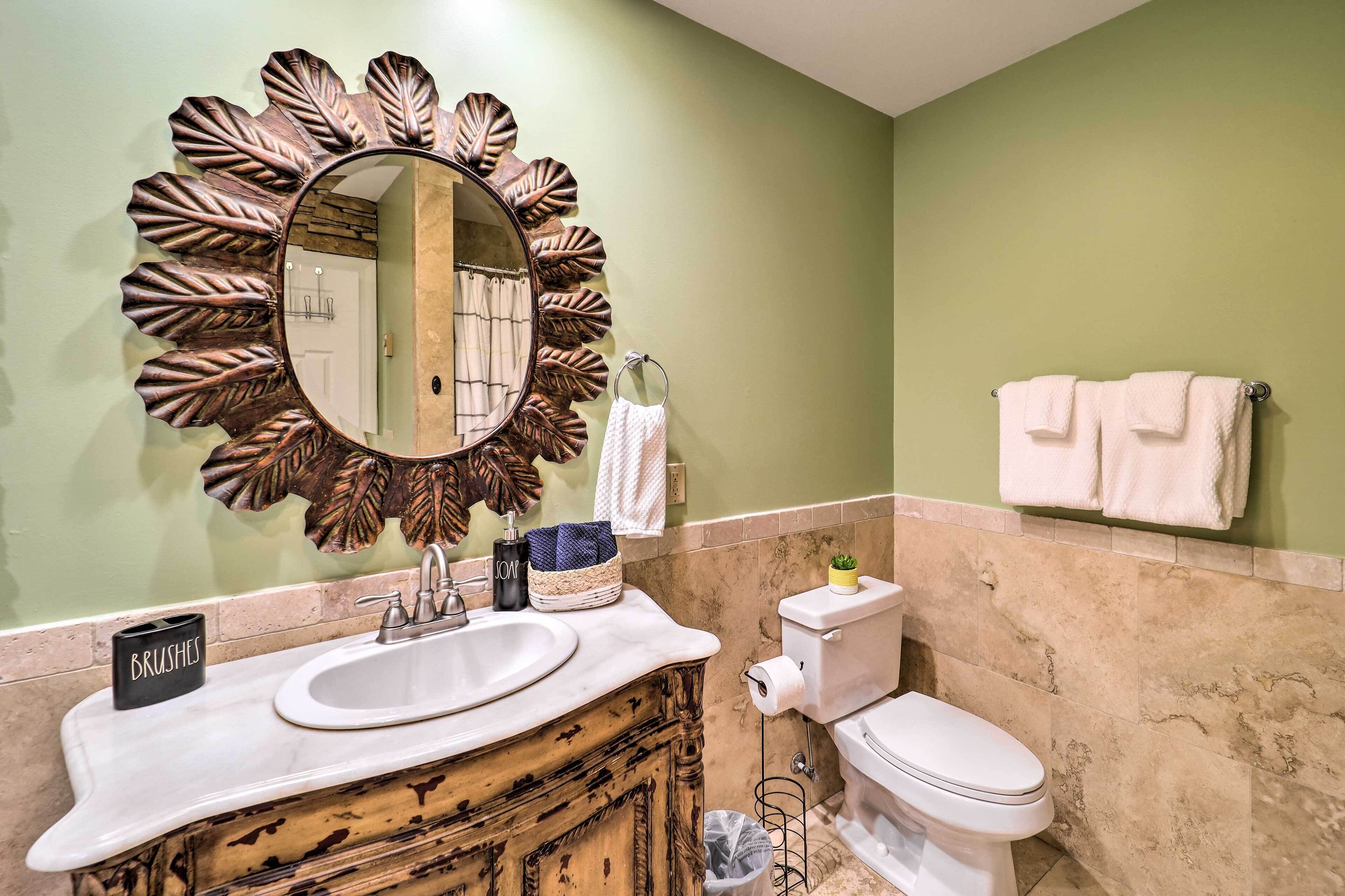A bathroom with a large mirror, a sink, a toilet, and a towel rack.