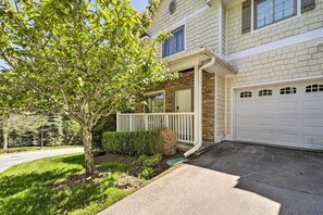 A two-story house with a stone facade, a white garage door, and a small porch with a white railing. - Lillys Mountain Escape (Banner Elk)