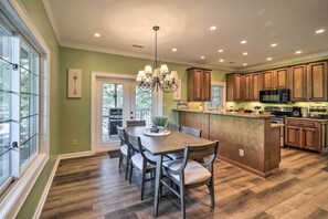 A kitchen with a dining table, chairs, wooden cabinets, a microwave, and a chandelier. - Lillys Mountain Escape (Banner Elk)