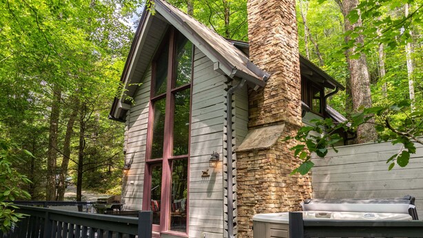 Une cabane dotée d’une terrasse, d’un bain à remous et d’un mur en pierre.