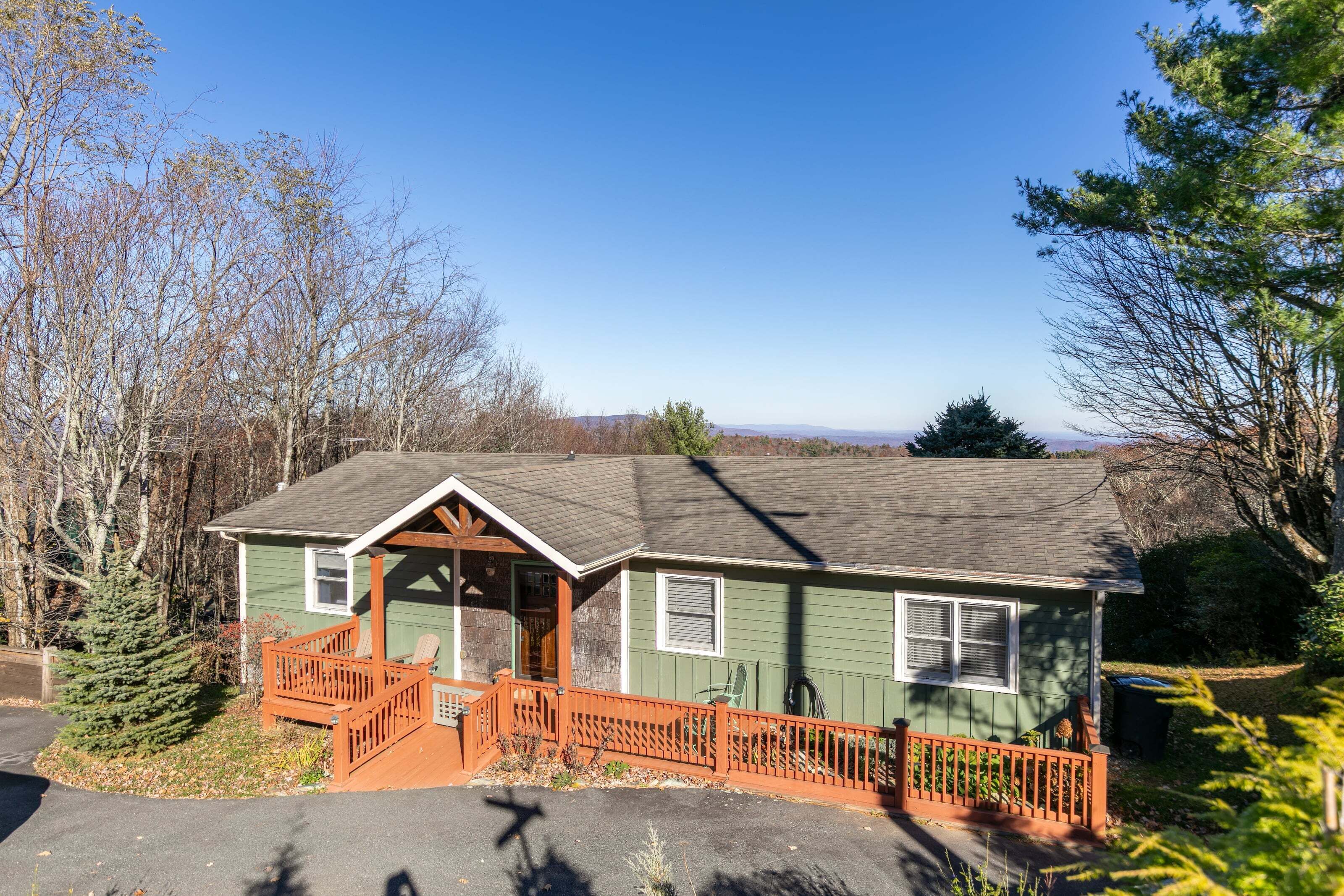 A small, single-story house with a porch, a small deck, and a fenced yard.