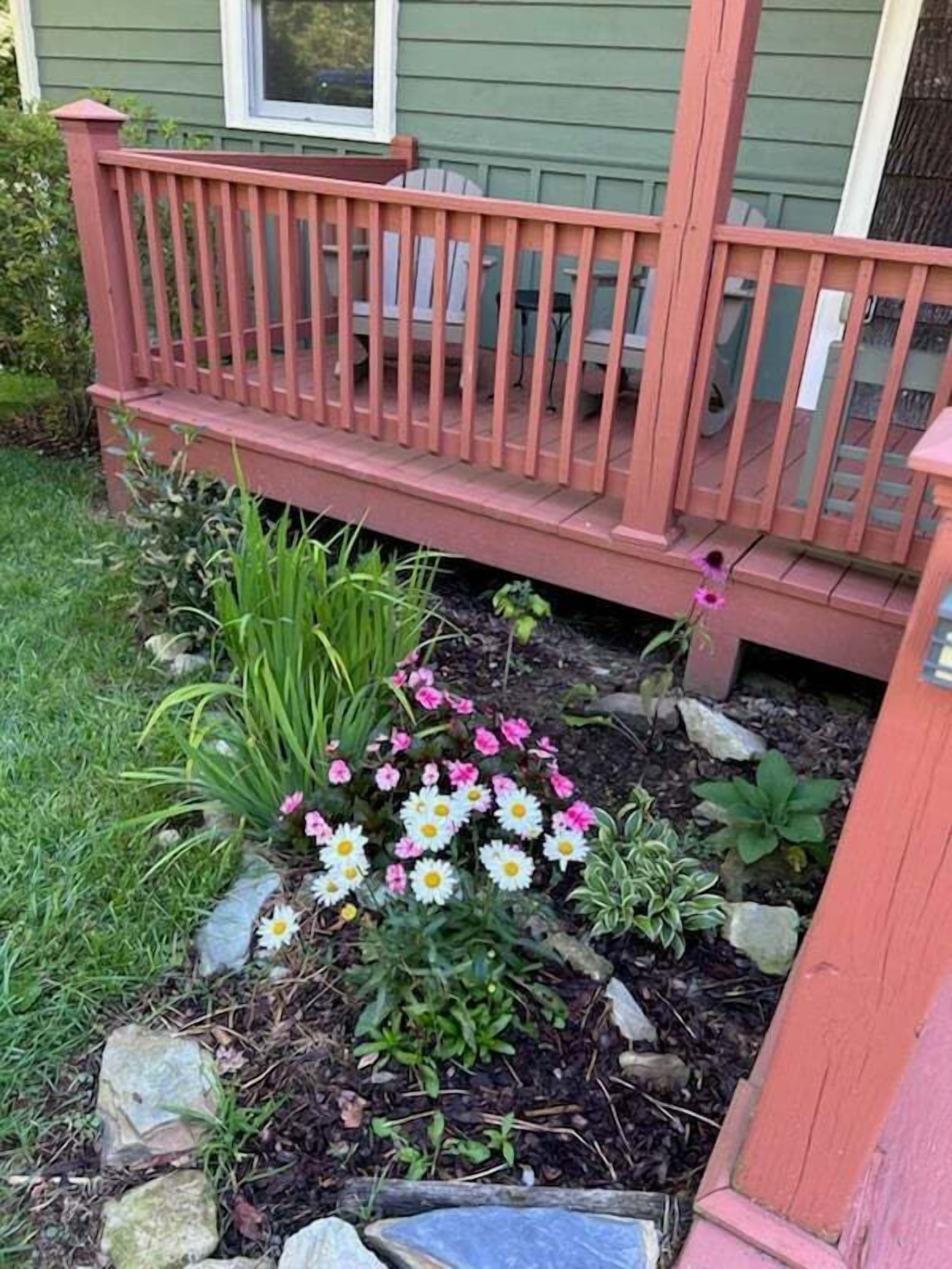 Un jardin doté d’une terrasse en bois et agrémenté de diverses plantes et fleurs.