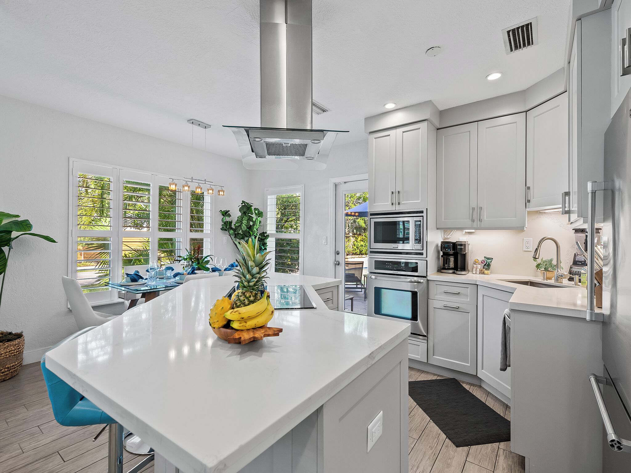 A modern kitchen with white cabinetry, stainless steel appliances, and a central island with a fruit bowl.