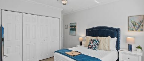 A bedroom with a bed, nightstands, a ceiling fan, and a wardrobe.
