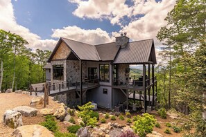 Ein modernes Haus mit einer Steinfassade, mehreren Terrassen und einem herrlichen Bergblick.