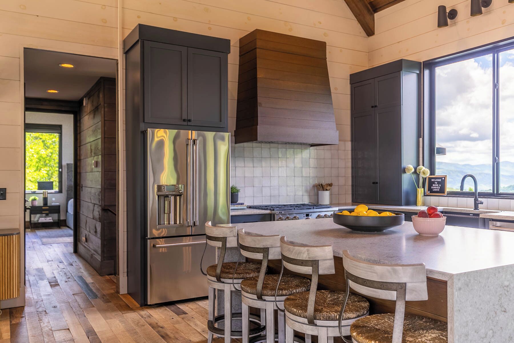 Una cocina moderna con una isla grande, electrodomésticos de acero inoxidable y vistas al exterior.