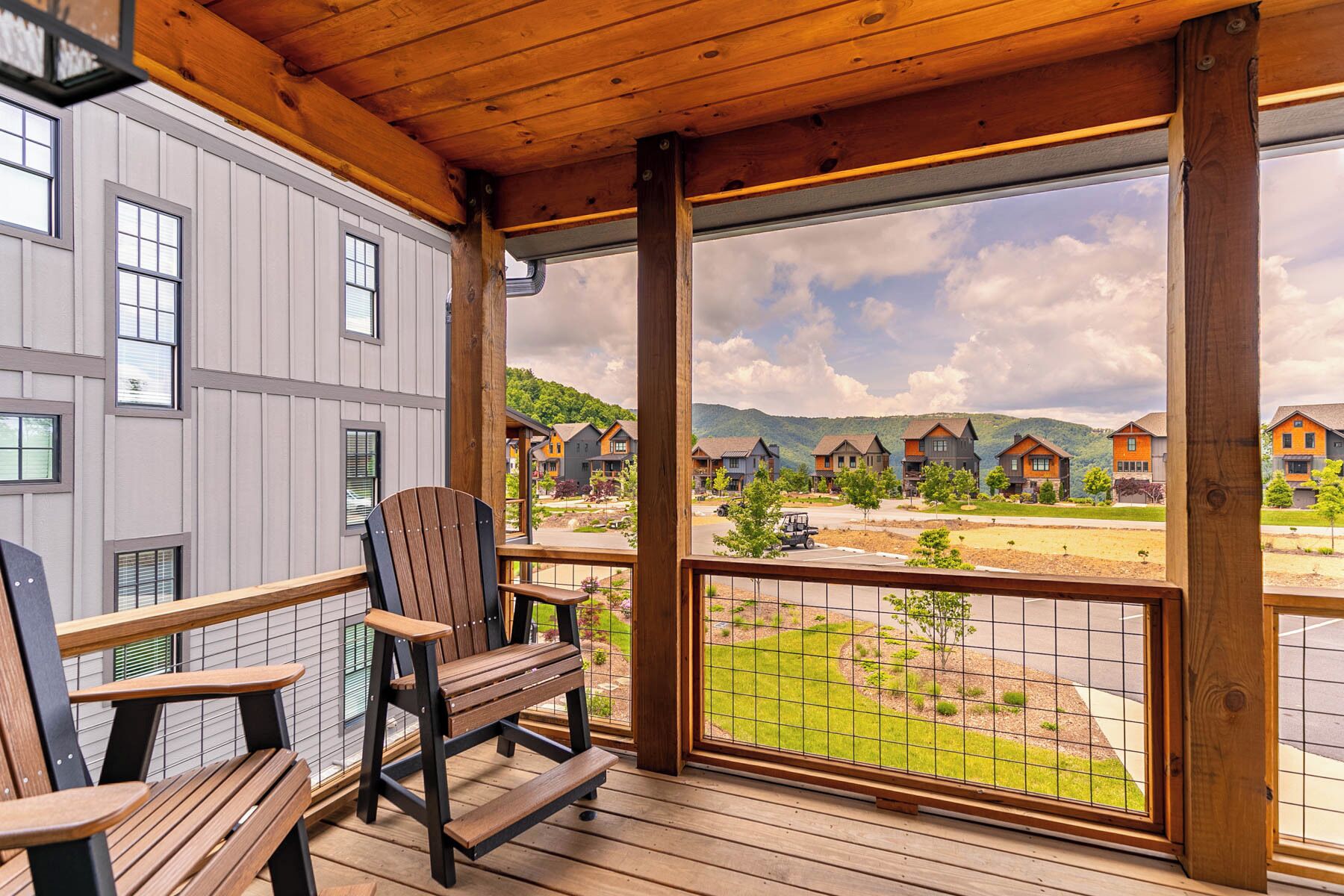 Une terrasse en bois offrant une vue sur un quartier résidentiel, avec des maisons et un paysage vallonné.