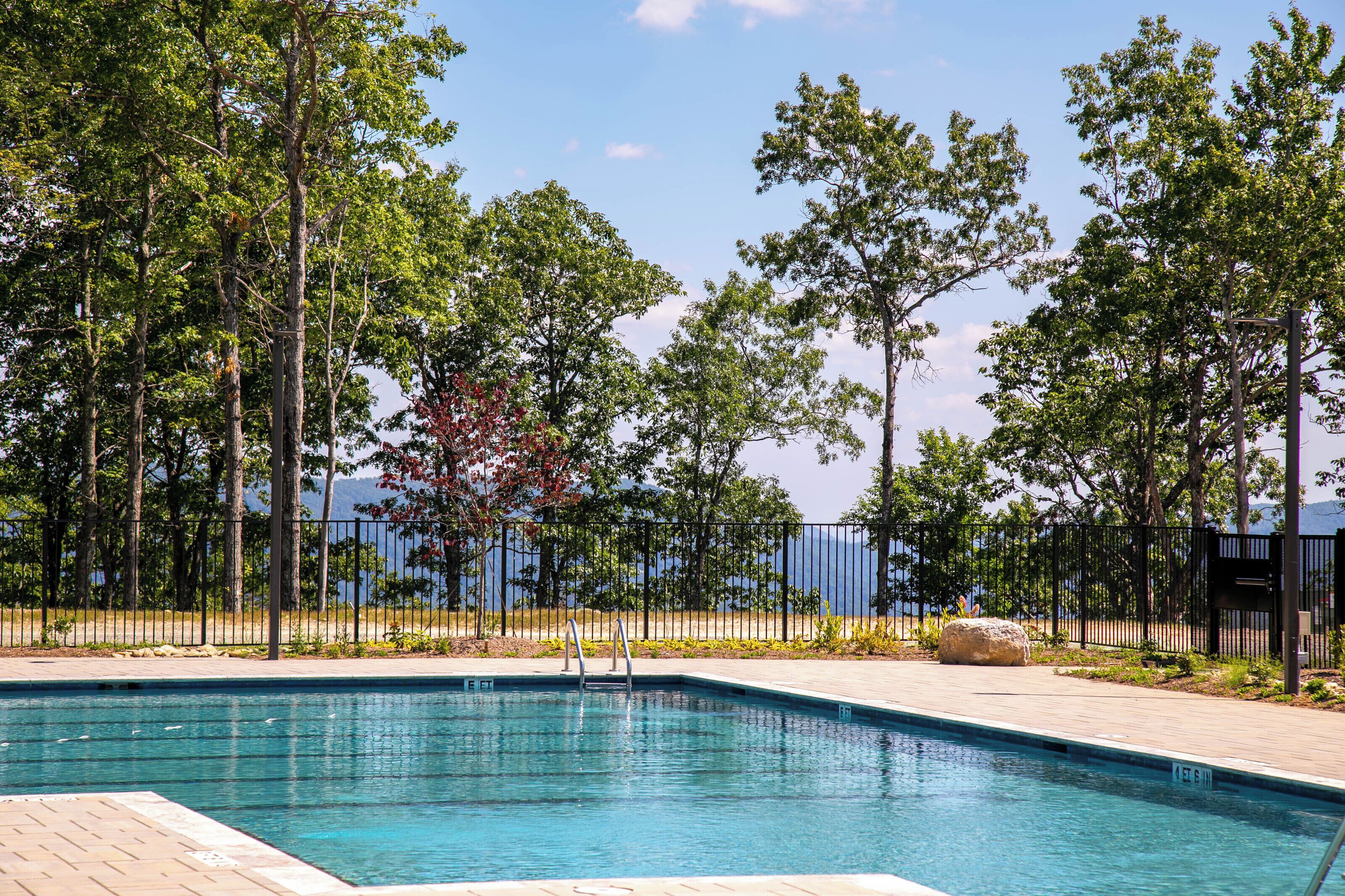Une piscine avec vue sur les arbres et un plan d’eau en arrière-plan.