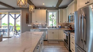 A modern kitchen with white cabinets, stainless steel appliances, and a large island. - Mountain Kandy at Blue Ridge Mountain Club (Lenoir)