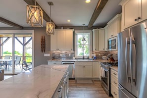 A modern kitchen with white cabinets, stainless steel appliances, and a large island. - Mountain Kandy at Blue Ridge Mountain Club (Lenoir)