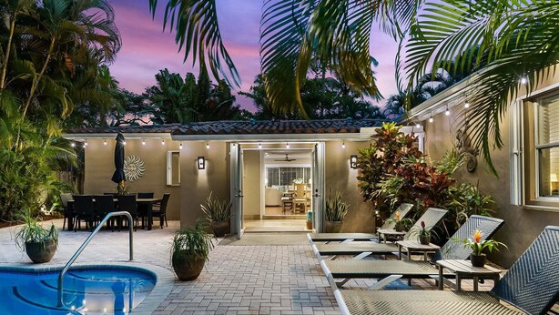 A pool area with lounge chairs, a dining set, and potted plants. - Palm Terrace With Private Pool Surrounded by Lush Gardens and Open Spaces (Fort Lauderdale)