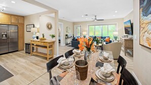A modern kitchen with a built-in refrigerator, wooden cabinets, and a dining area with a large table set for six. - Palm Terrace With Private Pool Surrounded by Lush Gardens and Open Spaces (Fort Lauderdale)