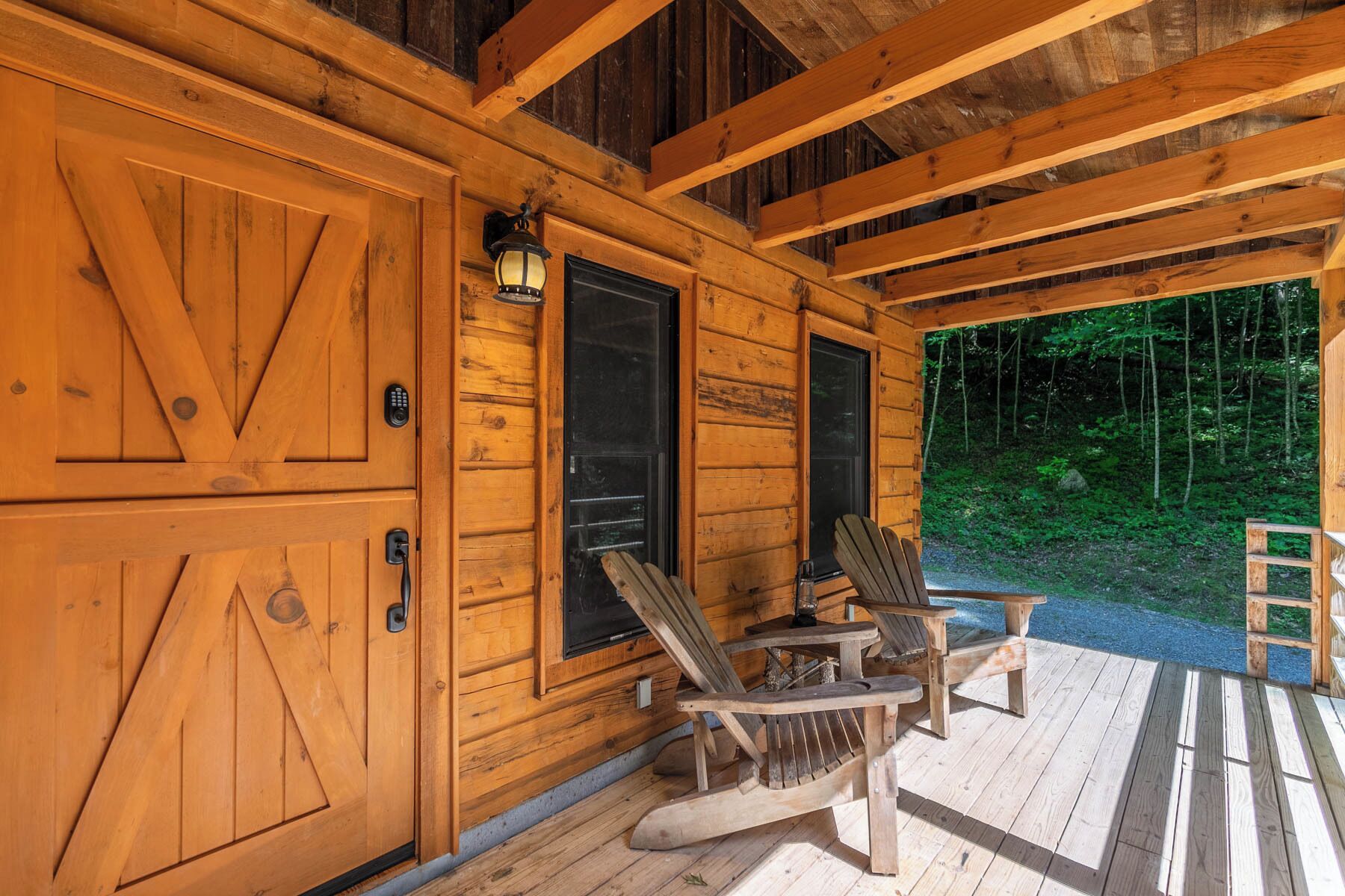 A wooden cabin with a porch, two rocking chairs, and a door with a keypad lock.