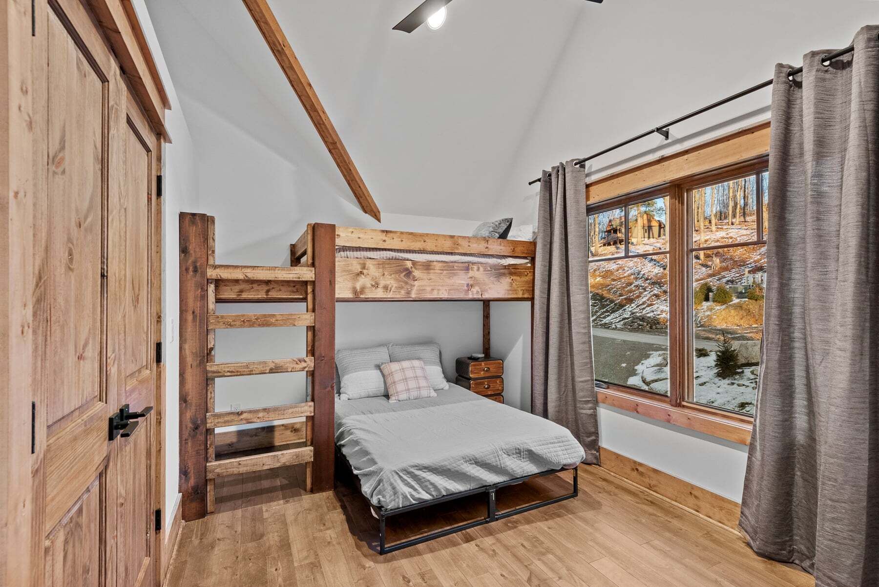 A bunk bed room with a window view of a snowy landscape.