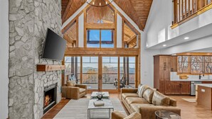 A spacious living area with a stone fireplace, leather sofas, and a large TV.