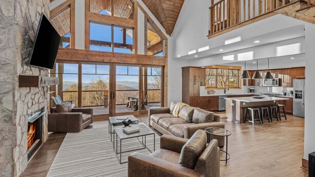 A spacious living area with a fireplace, leather sofas, and a large window overlooking a mountainous landscape.