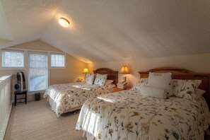 A bedroom with two beds, a ceiling fan, a heater, and a window with blinds.