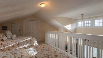 A bedroom with two beds, a white railing, a door, and a window.