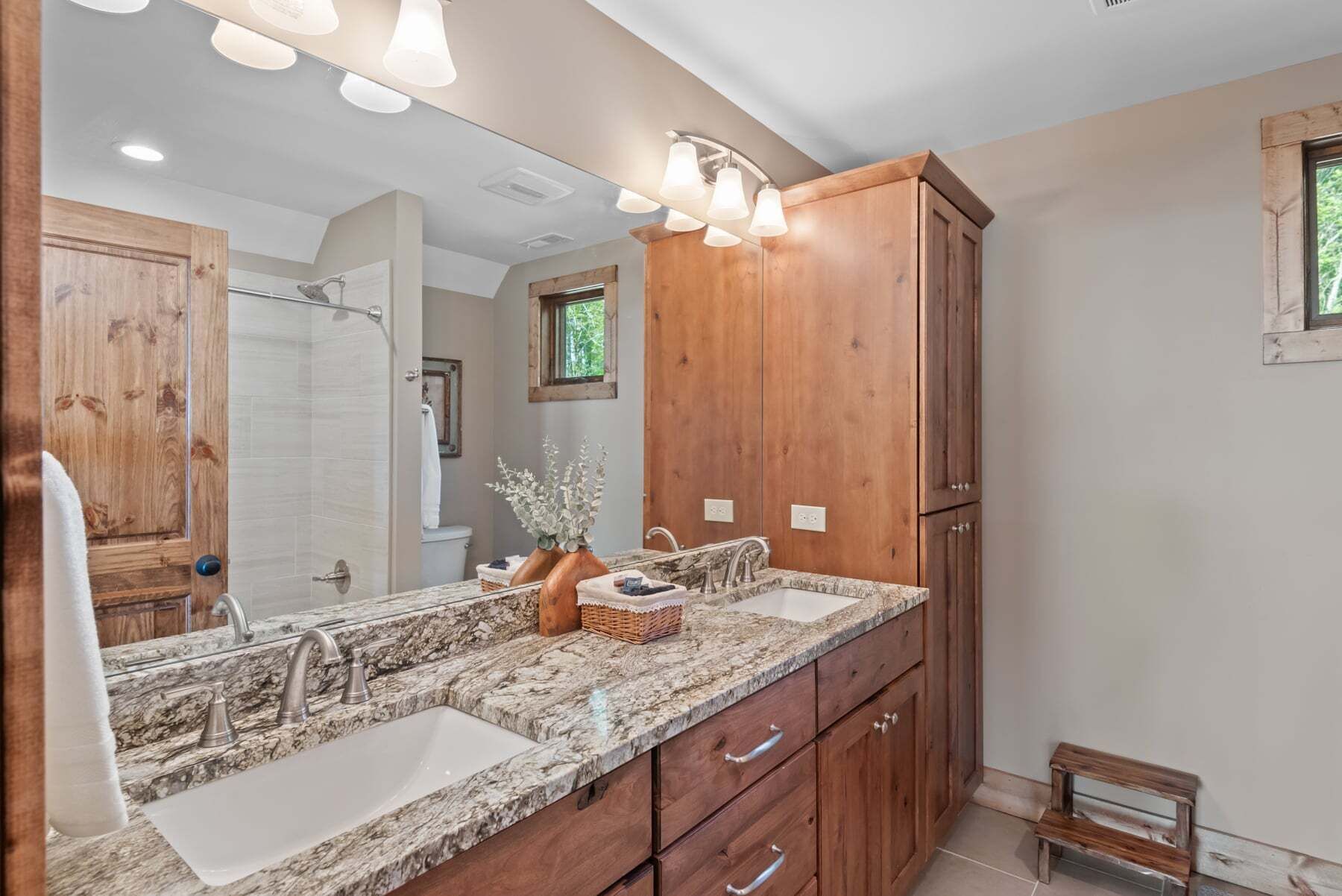 A bathroom with a double sink, wooden cabinets, and a mirror.