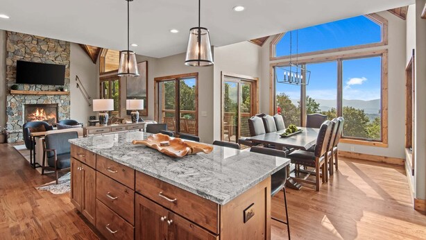 A spacious kitchen with a stone fireplace, large windows, and a dining area with a view. - Grandview Pointe (Banner Elk)