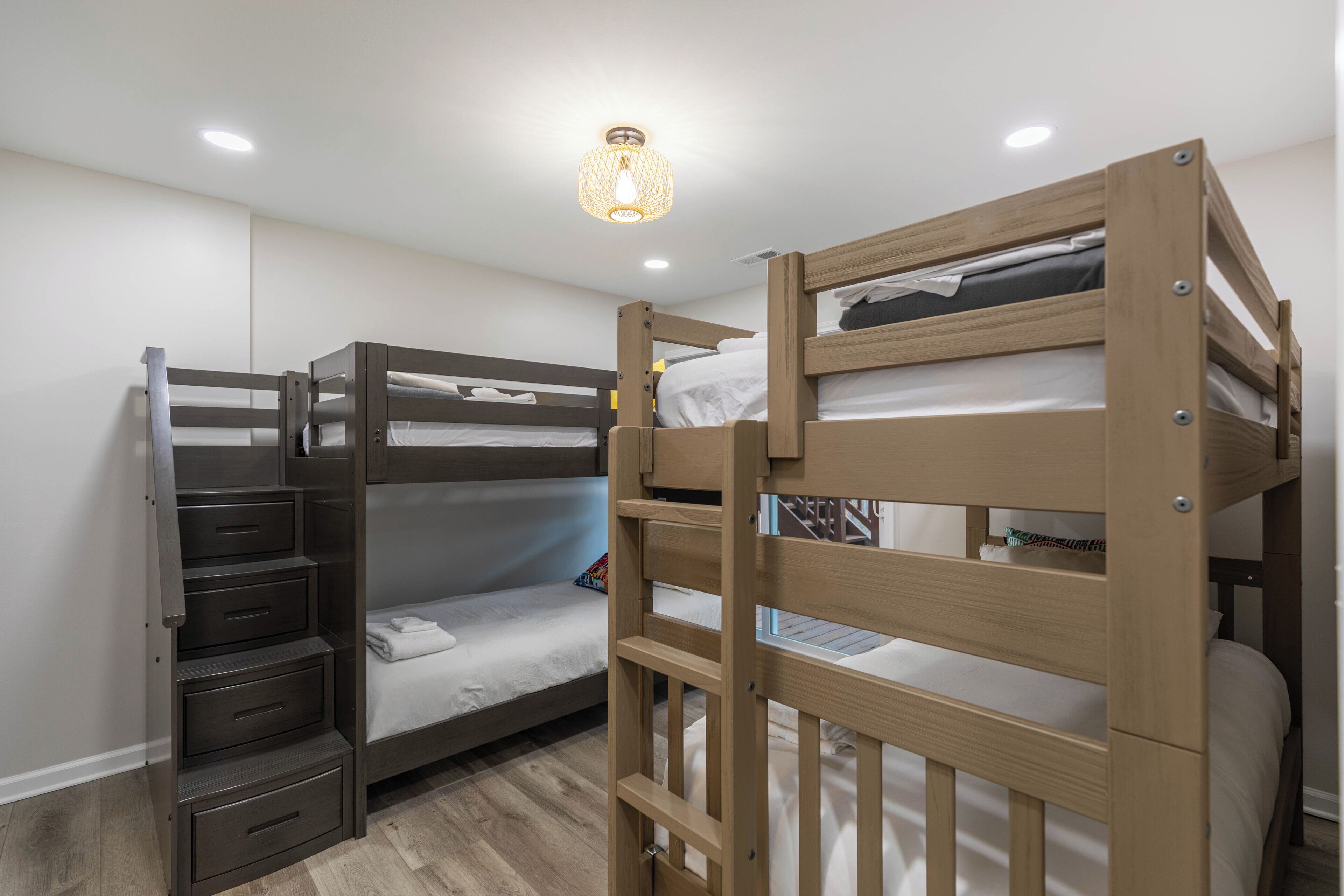 Une chambre avec un lit superposé, une échelle en bois, un bureau et une lampe suspendue.
