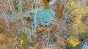 Luftaufnahme eines Hauses, umgeben von Bäumen mit Herbstlaub.