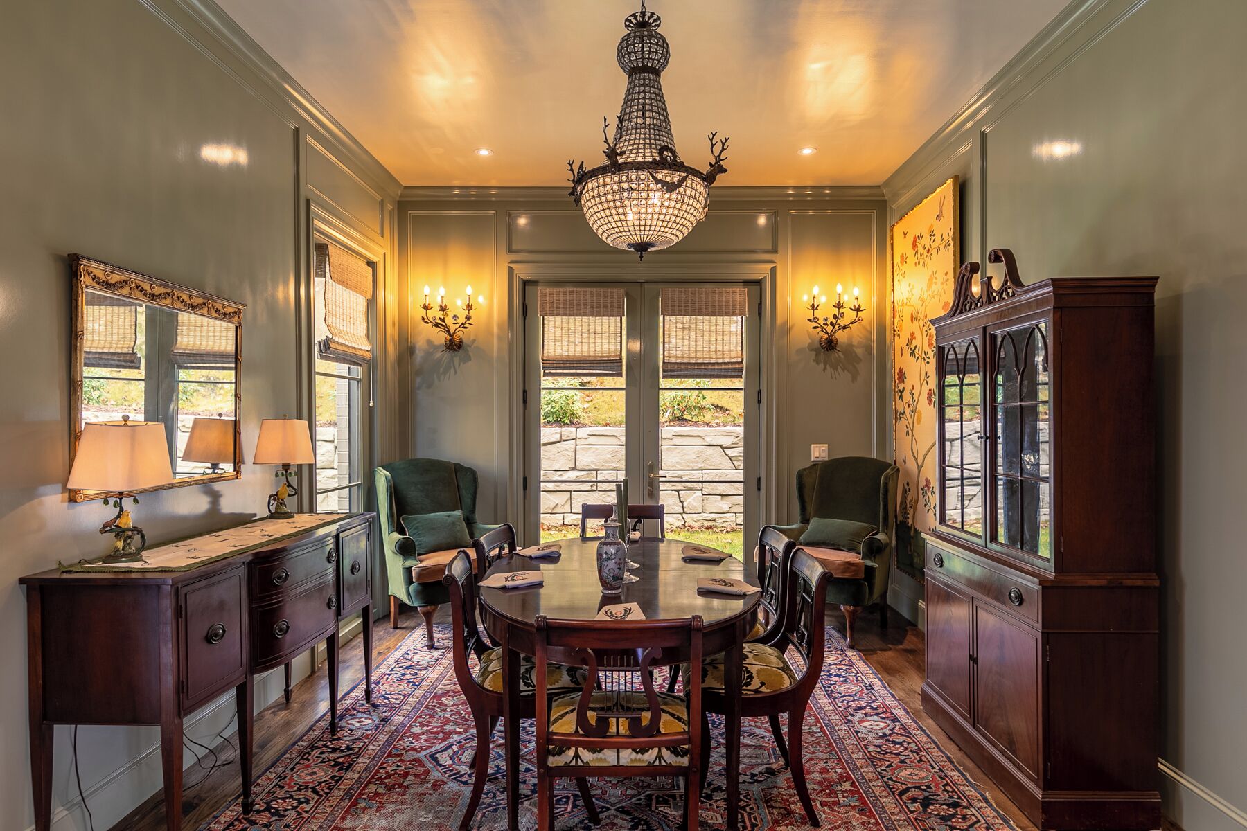 A dining room with a chandelier, two chairs, a table, and a cabinet.